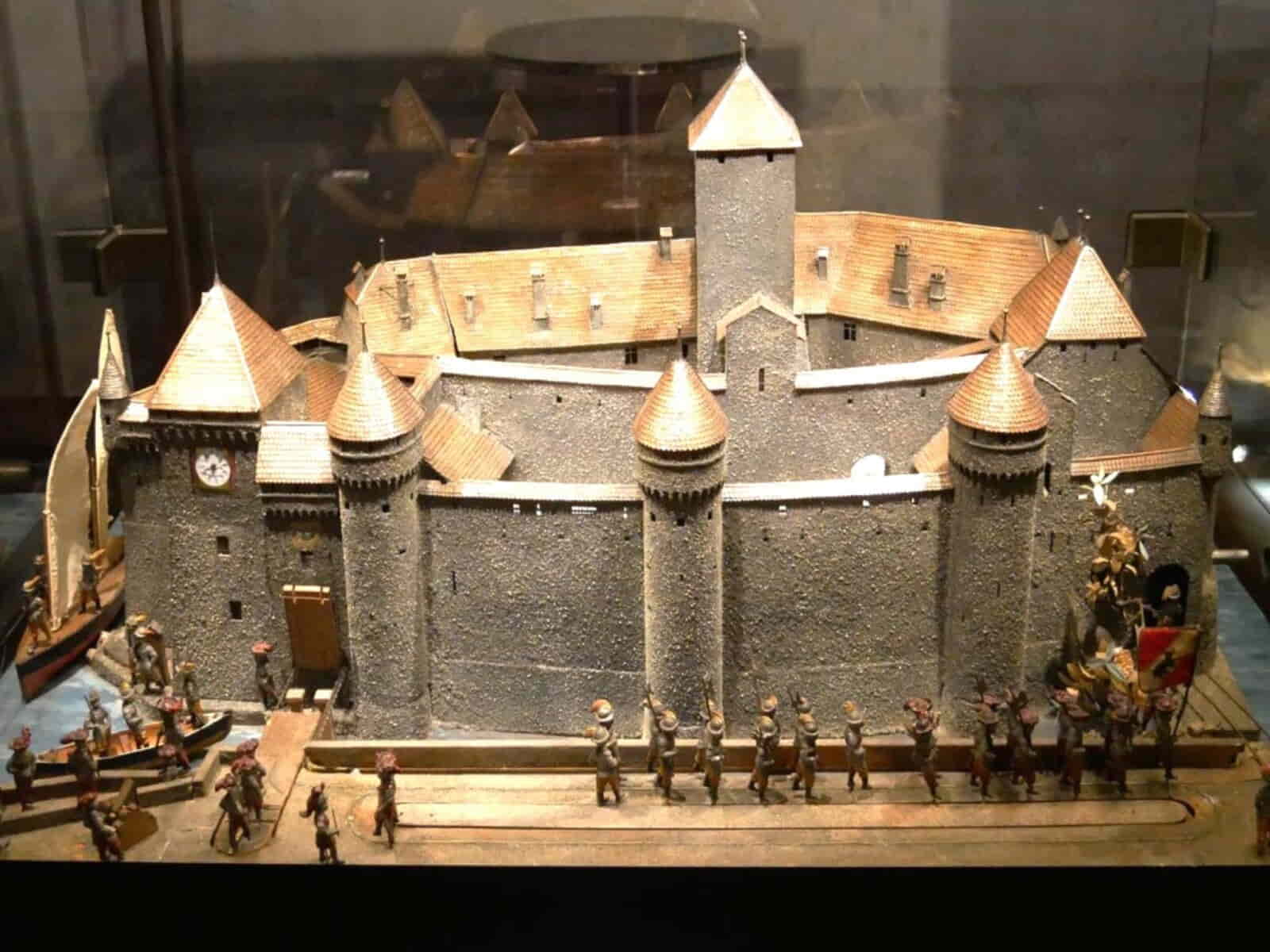 Interior courtyard of Château de Chillon, featuring medieval stone walls, arched windows, and a sunny open space with visitors exploring the historic site.