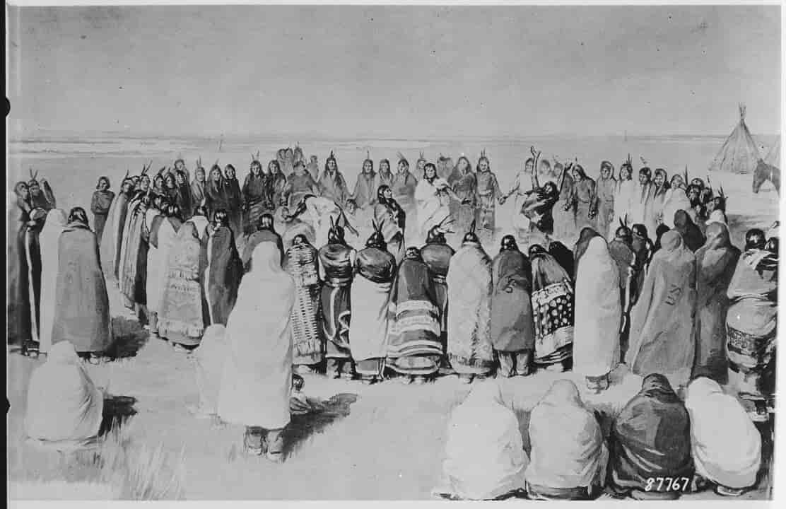 Archival photo of U.S. soldiers standing over bodies after the Wounded Knee massacre, 1890