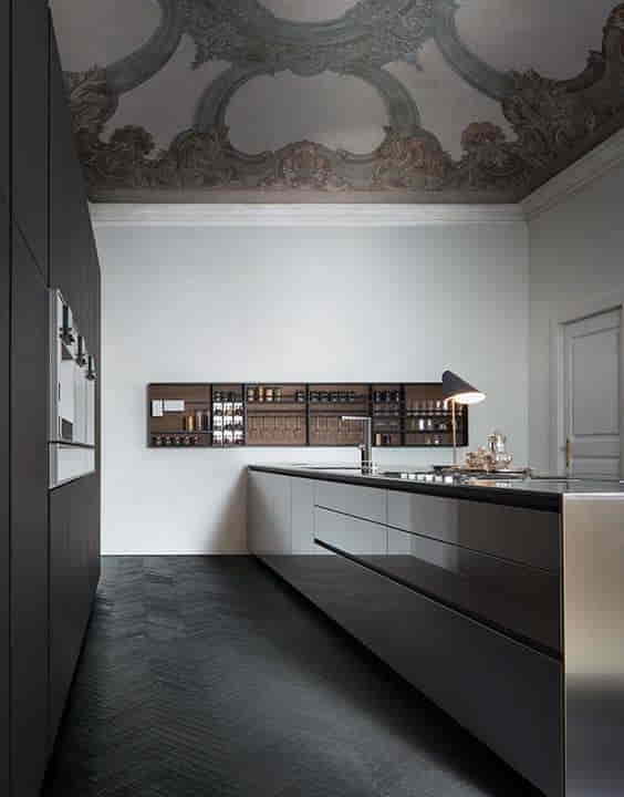 Contemporary kitchen island with dark cabinetry, built-in sink, and modern pendant lights in a spacious kitchen.