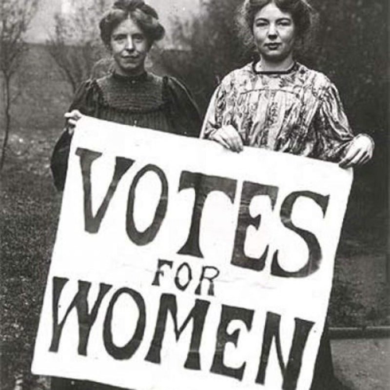 Black and white photograph of Emmeline Pankhurst standing defiantly with fellow suffragettes during a protest.