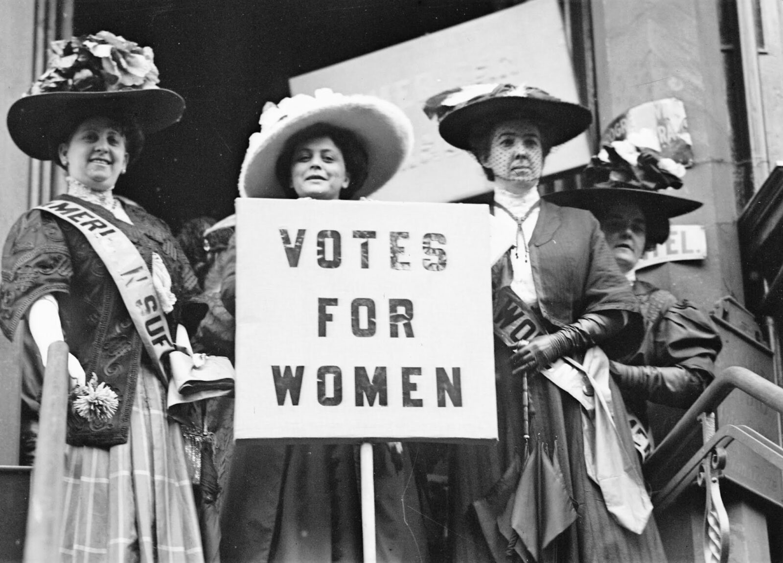Black and white photo of women suffragists holding signs during a peaceful protest, representing early 20th-century activism linked to Mother’s Day.
